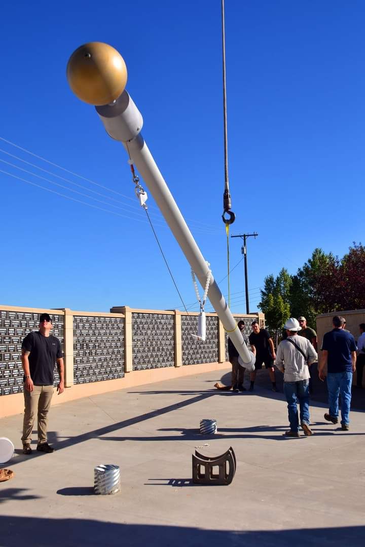 A crane is lifting a pole with a gold ball on top