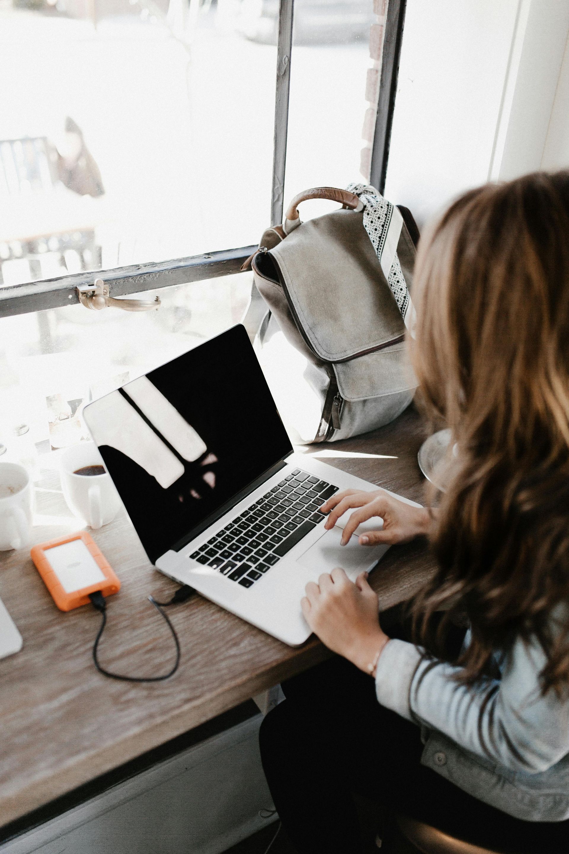 A woman is sitting at a table using a laptop computer.