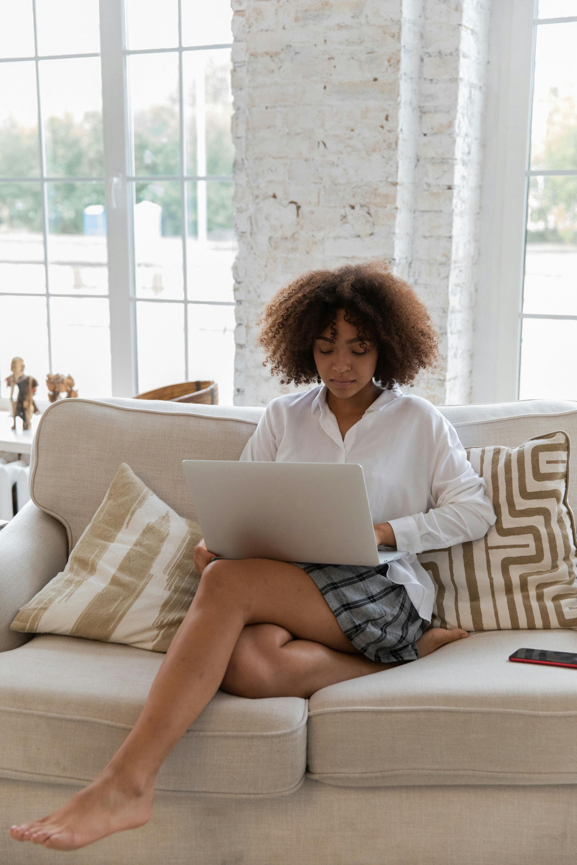 A woman is sitting on a couch using a laptop computer.