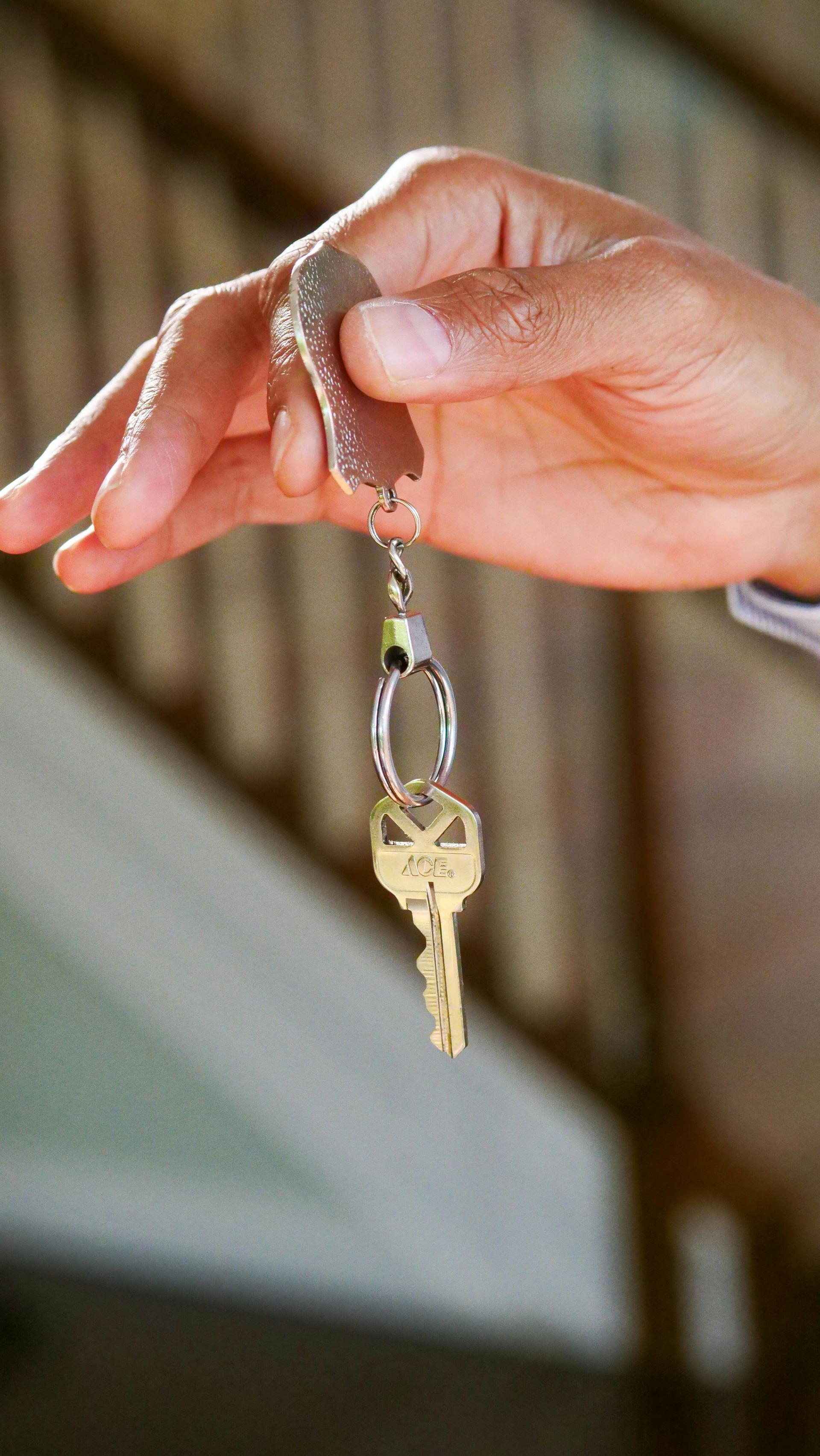 A person is holding a key in their hand in front of a staircase.