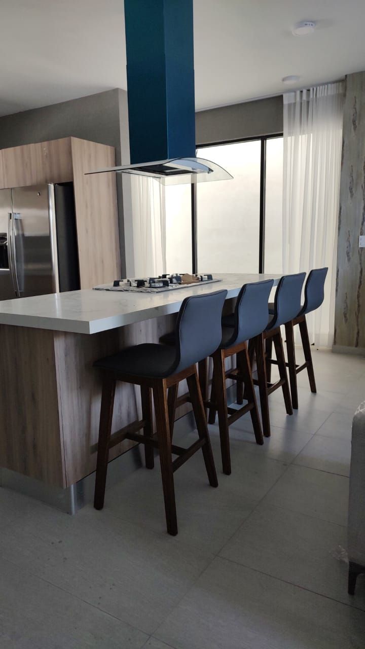 Una cocina con una gran isla y taburetes y un horno de leña.