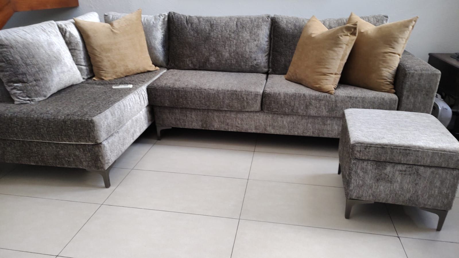 Una sala de estar con un sofá seccional y una otomana.