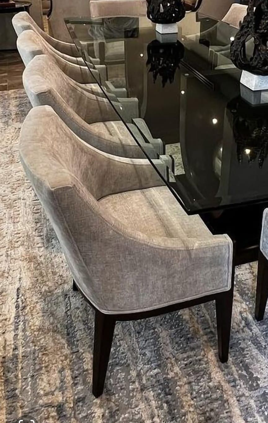 Una fila de sillas junto a una mesa de comedor de cristal.