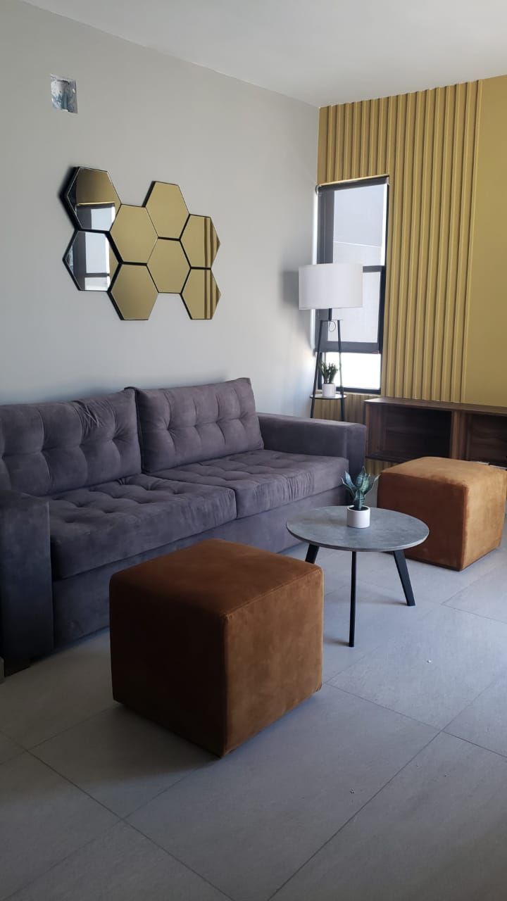 Una sala de estar con un sofá y dos otomanas.