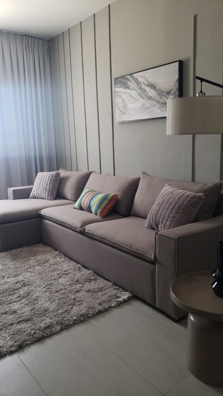 Una sala de estar con un gran sofá seccional y una alfombra.