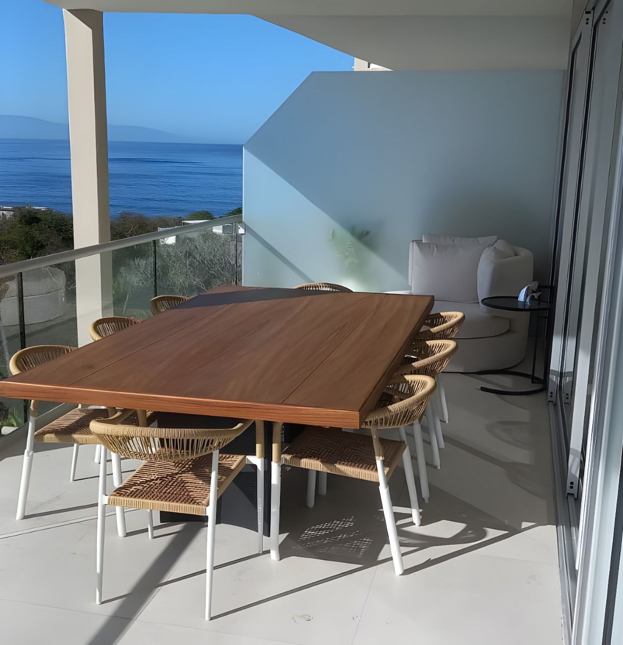 Una mesa y sillas en un balcón con vista al mar.