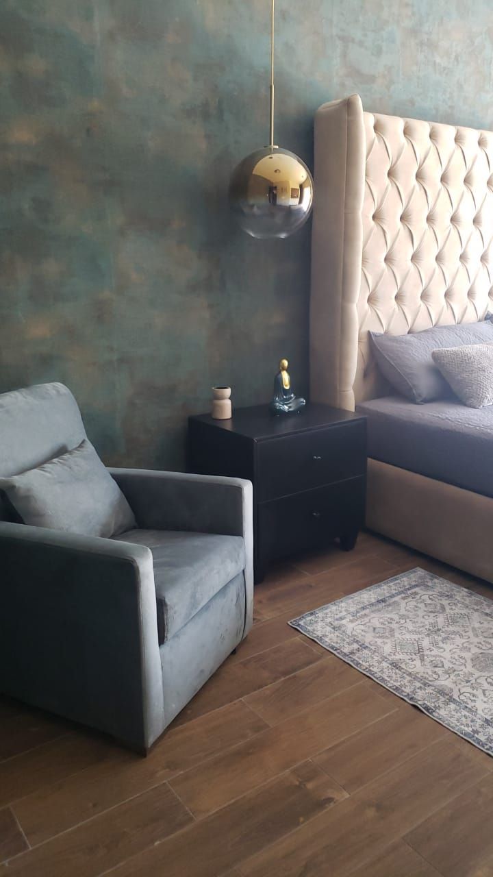 Un dormitorio con cama, silla, mesita de noche y alfombra.