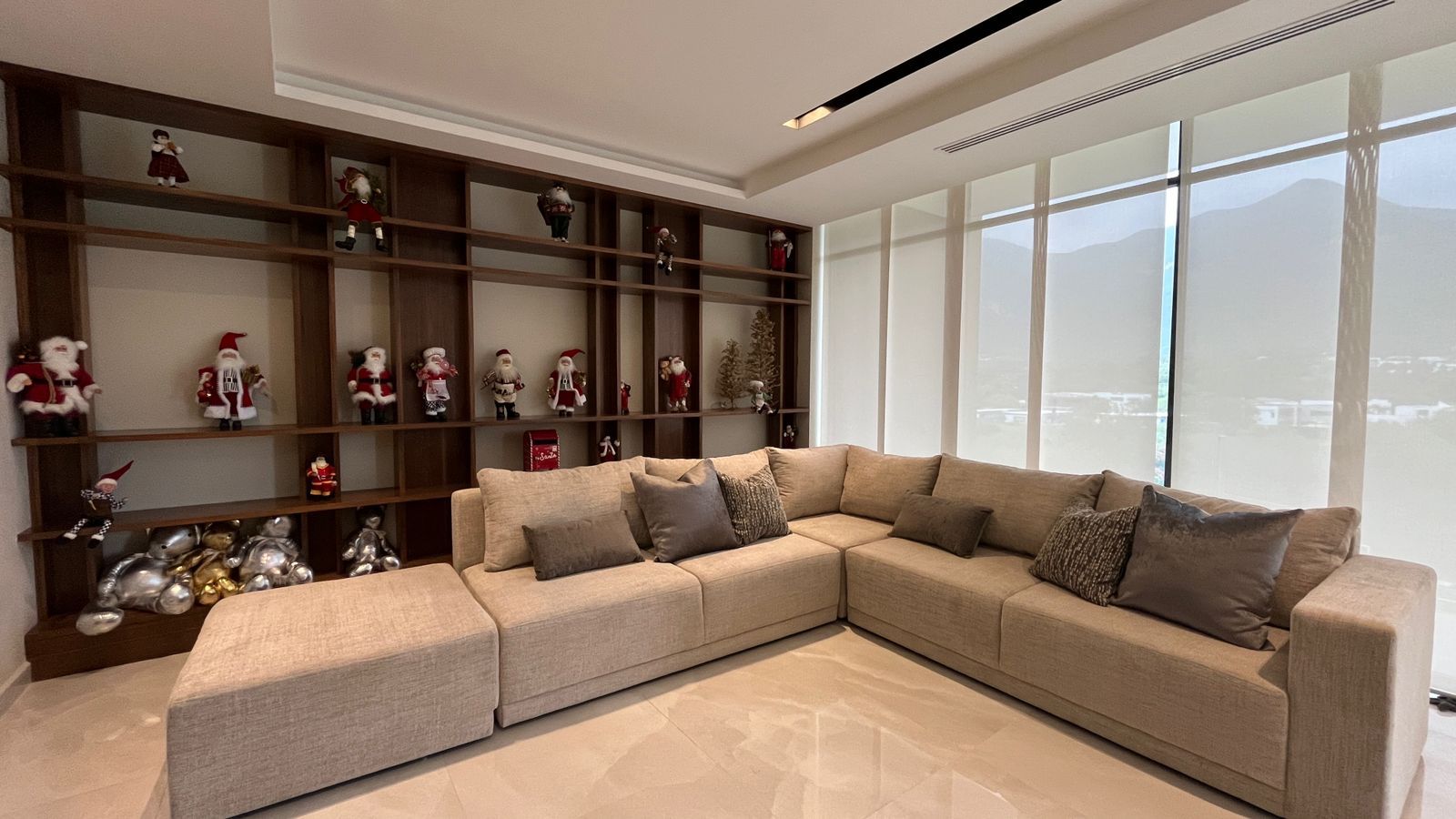 Una sala de estar con un gran sofá seccional y estantes llenos de adornos navideños.