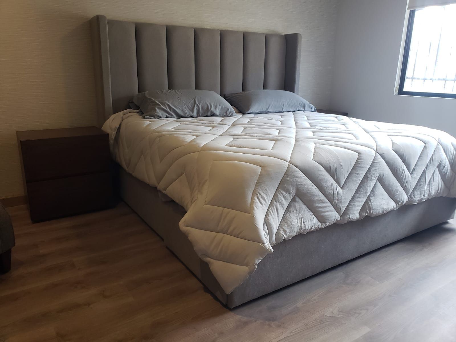 Un dormitorio con cama, mesita de noche y ventana.