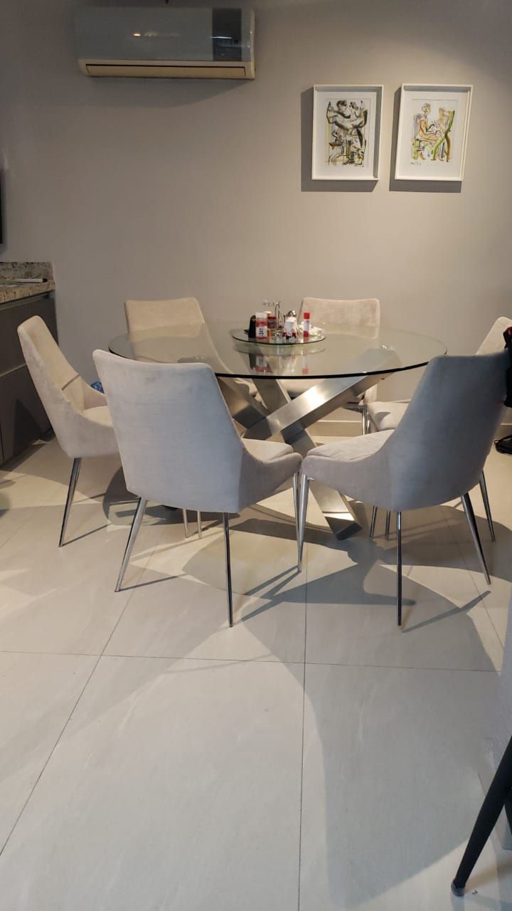 Un comedor con una mesa de cristal y sillas.