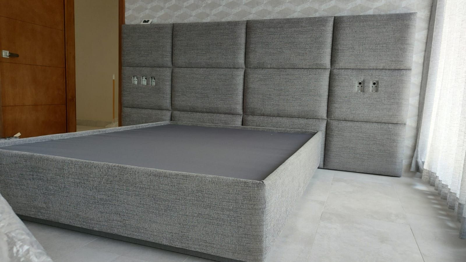 Una cama con cabecero se encuentra en un dormitorio al lado de una ventana.