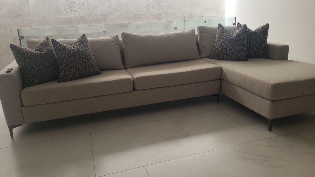 Un gran sofá seccional está colocado sobre un piso de baldosas en una sala de estar.