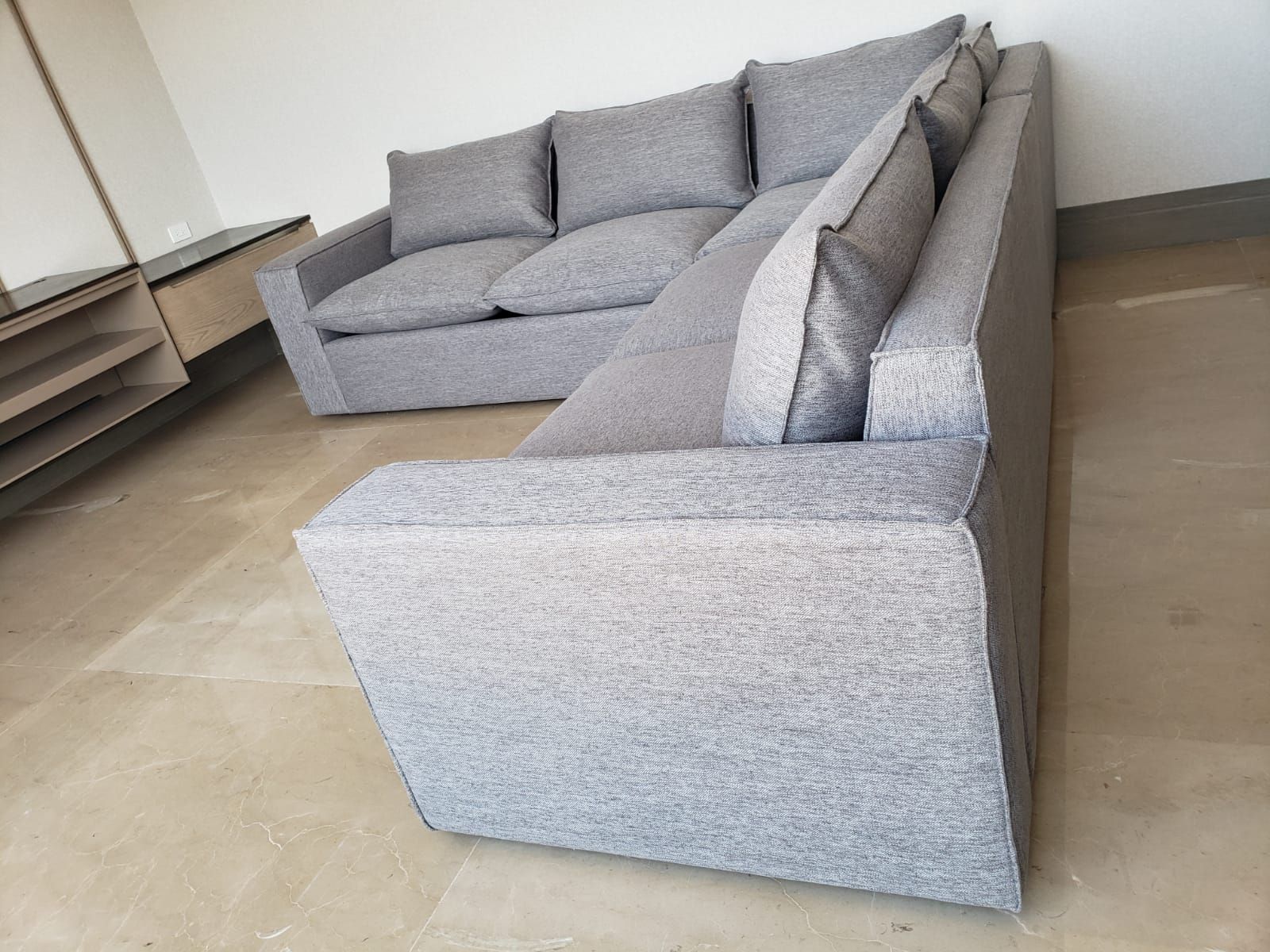 Un sofá seccional gris está sobre un piso de baldosas en una sala de estar.