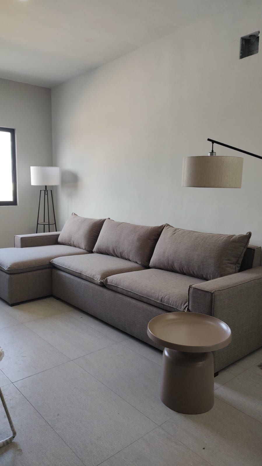 Una sala de estar con sofá, mesa, lámpara y ventana.