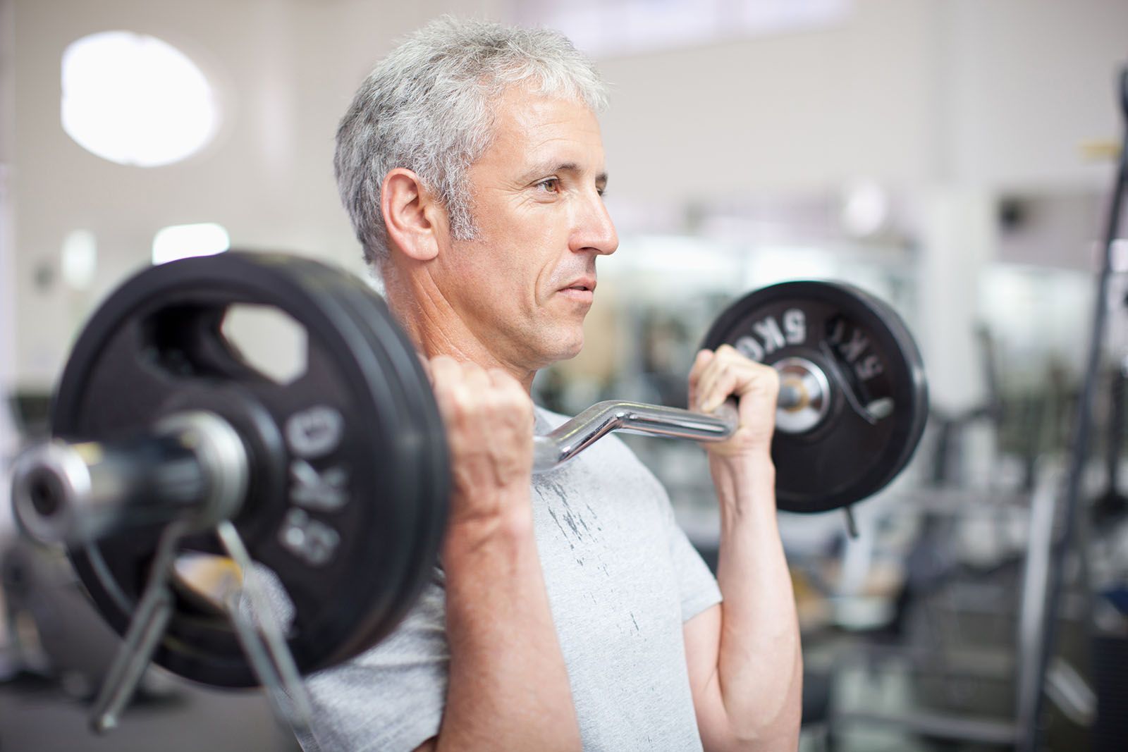 A man is lifting a barbell in a gym.
