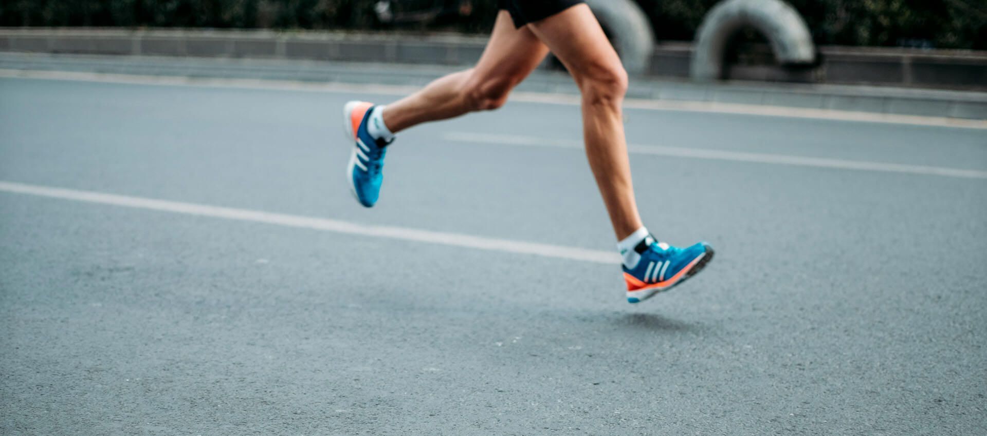 A person is running on a street wearing blue shoes.