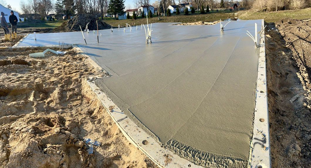 A concrete foundation is being built in a dirt field.