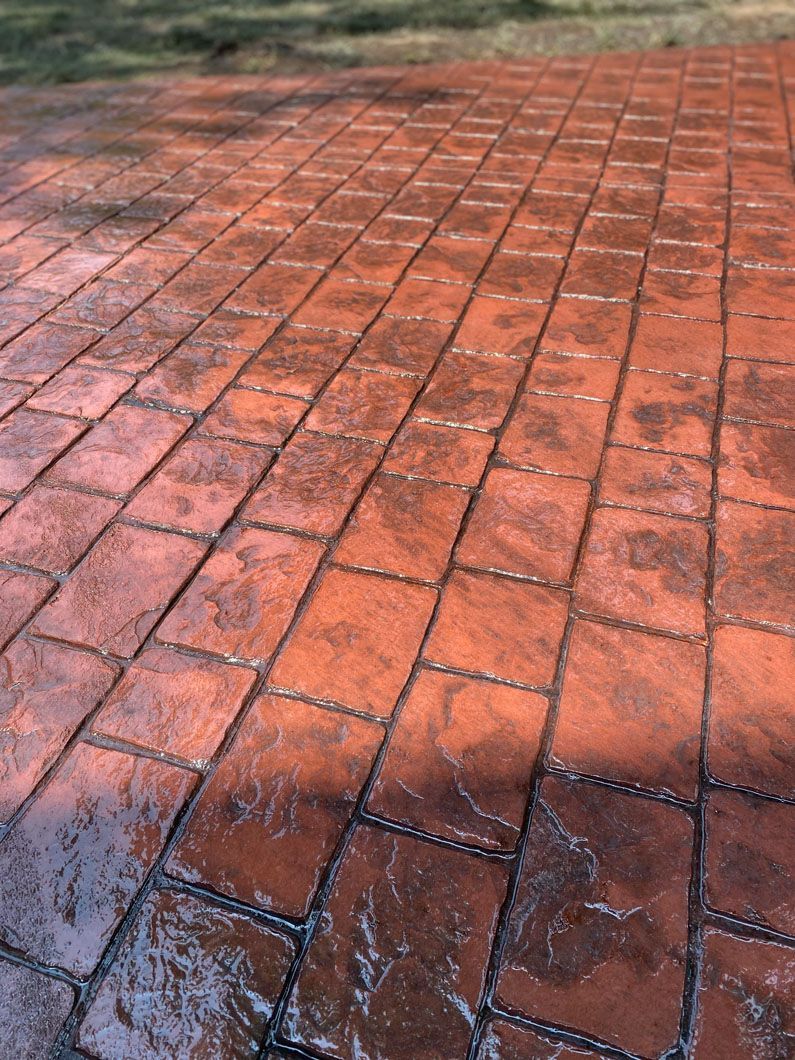 A close up of a brick driveway with a shadow on it.