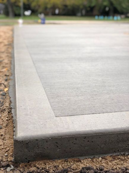 A close up of a concrete driveway with a concrete curb.