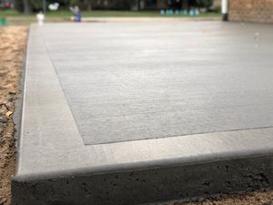 A close up of a concrete patio being built in front of a house.