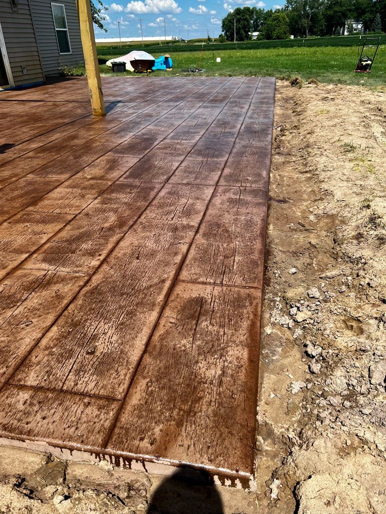 A person is standing on a concrete walkway that looks like wood.
