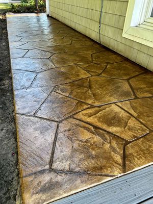 A concrete walkway with a stone pattern is sitting next to a house.