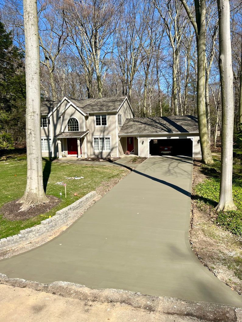 A driveway leading to a large house in the woods.