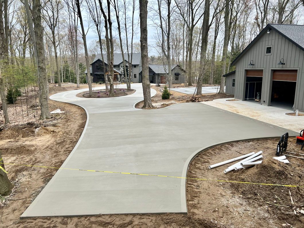 A concrete driveway is being built in front of a house in the woods.