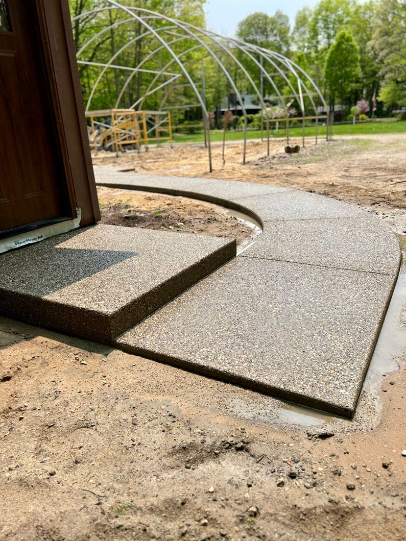 A concrete walkway is being built in front of a greenhouse.