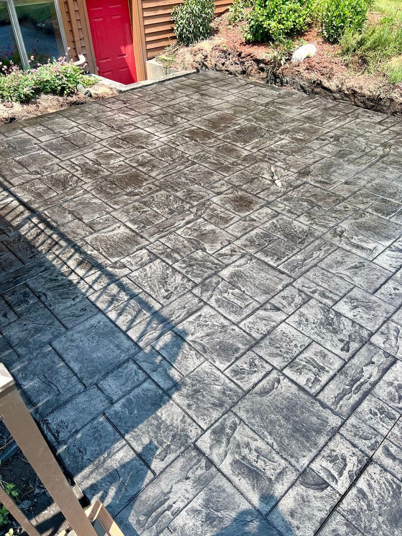 A concrete patio with a red door in the background.