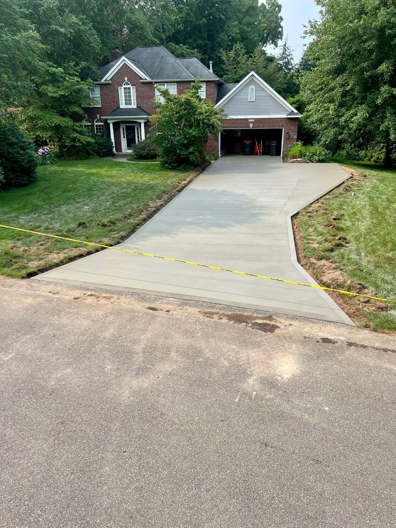 A brick house with a concrete driveway leading to it.