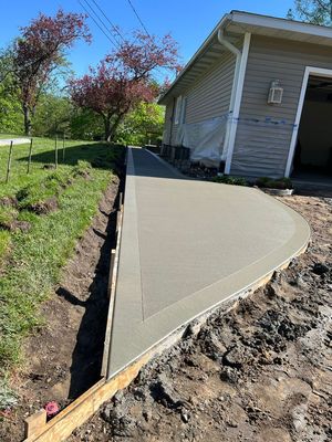 A concrete walkway is being built in front of a house.