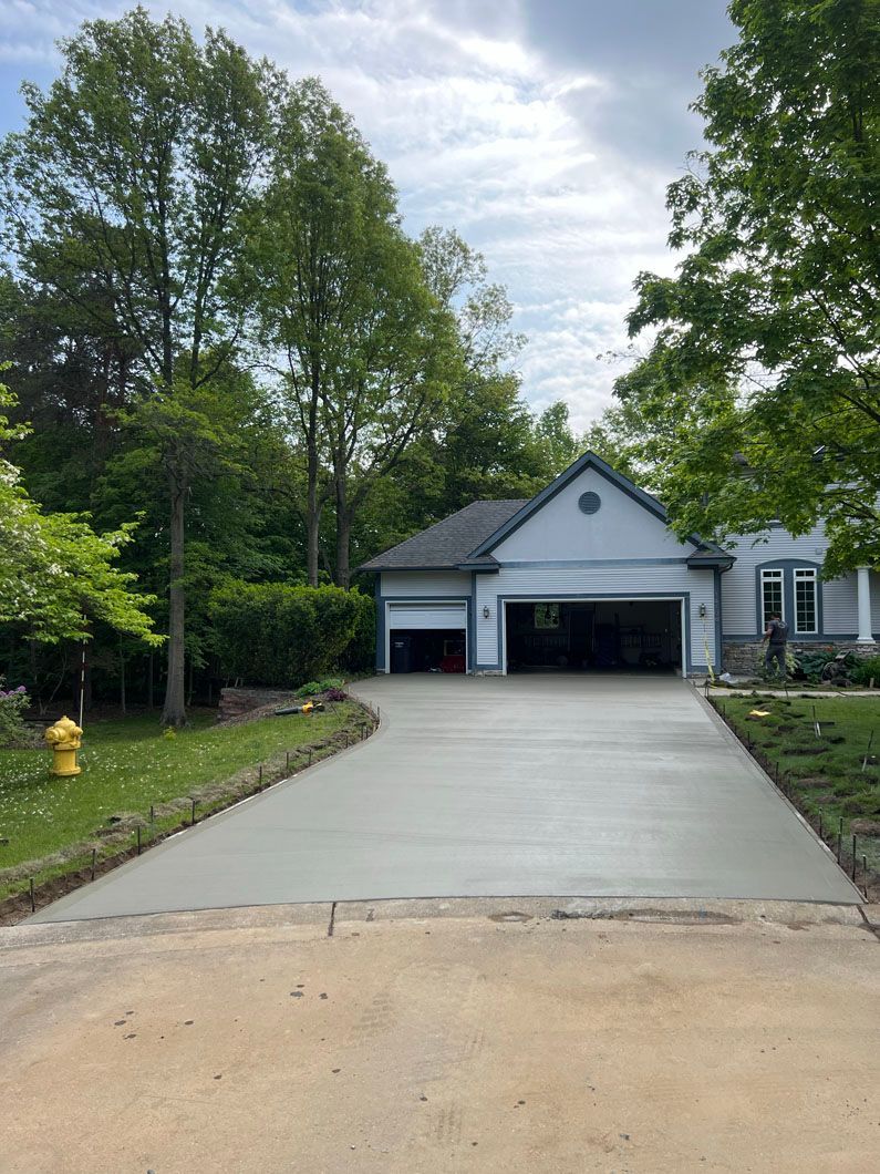 A concrete driveway leading to a house with a garage and a fire hydrant.