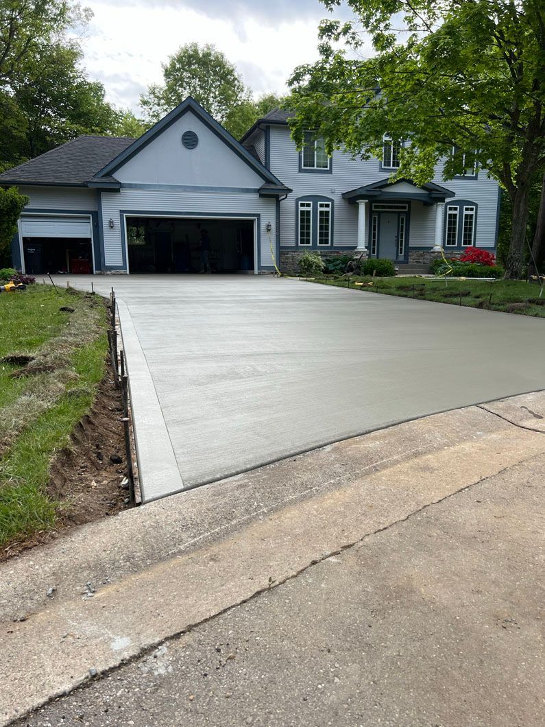 A concrete driveway is being built in front of a large house.