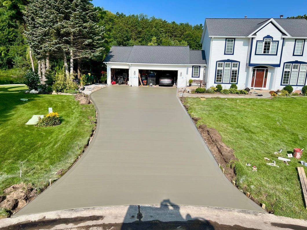 A concrete driveway is being built in front of a large white house.
