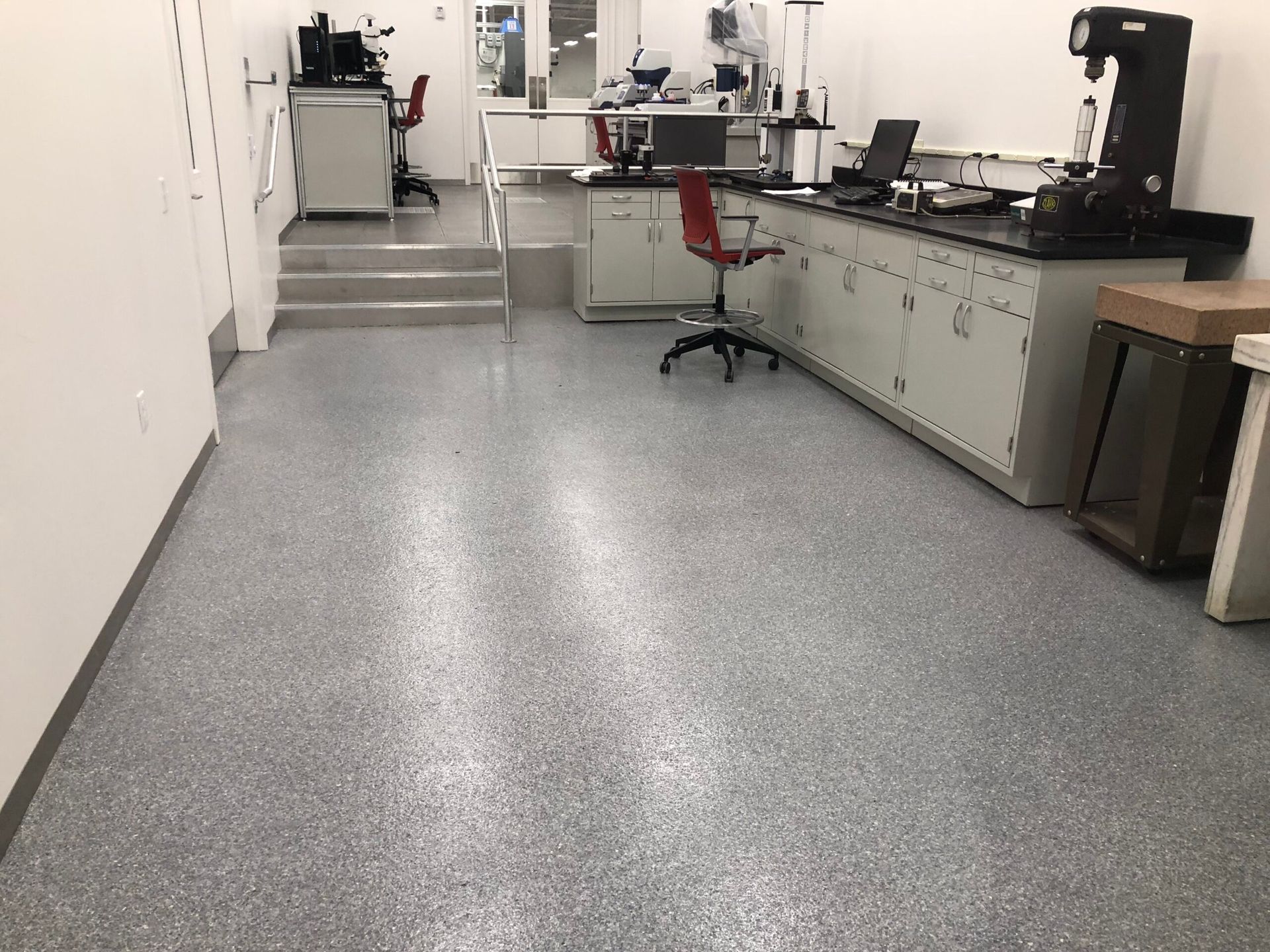 A laboratory with a gray floor and a red chair.