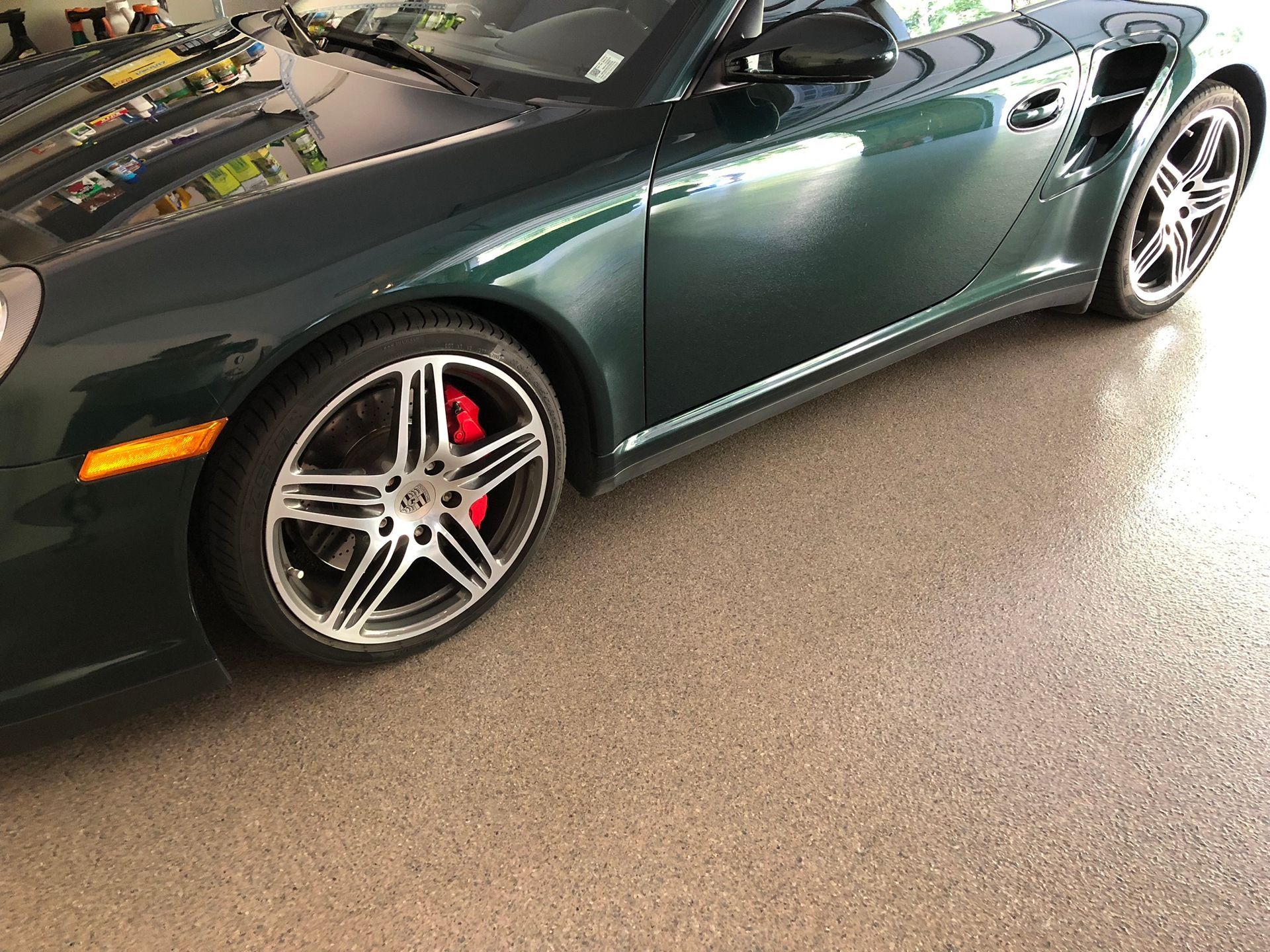 A green porsche 911 turbo is parked in a garage.