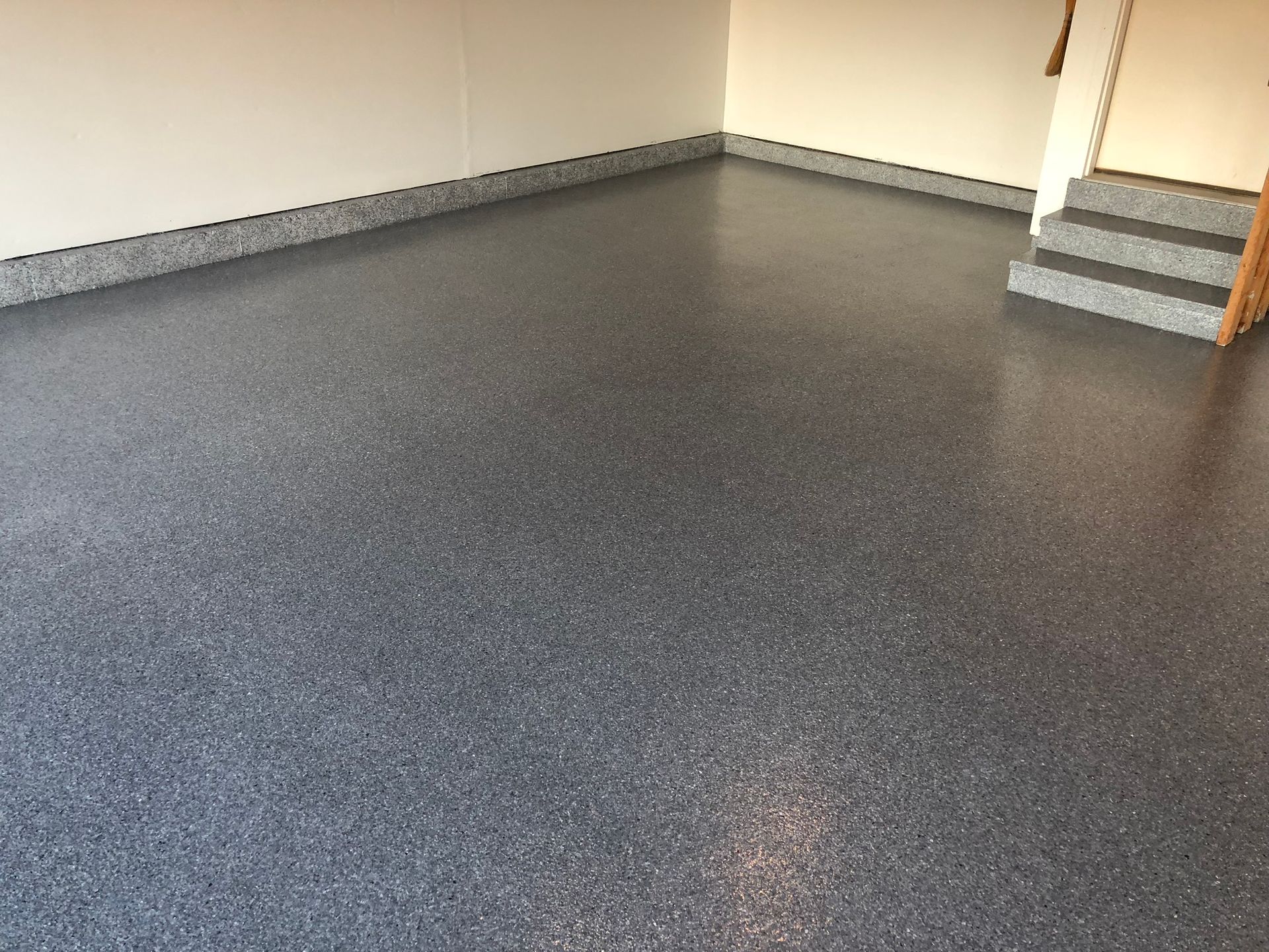 A garage with a staircase and a gray floor.