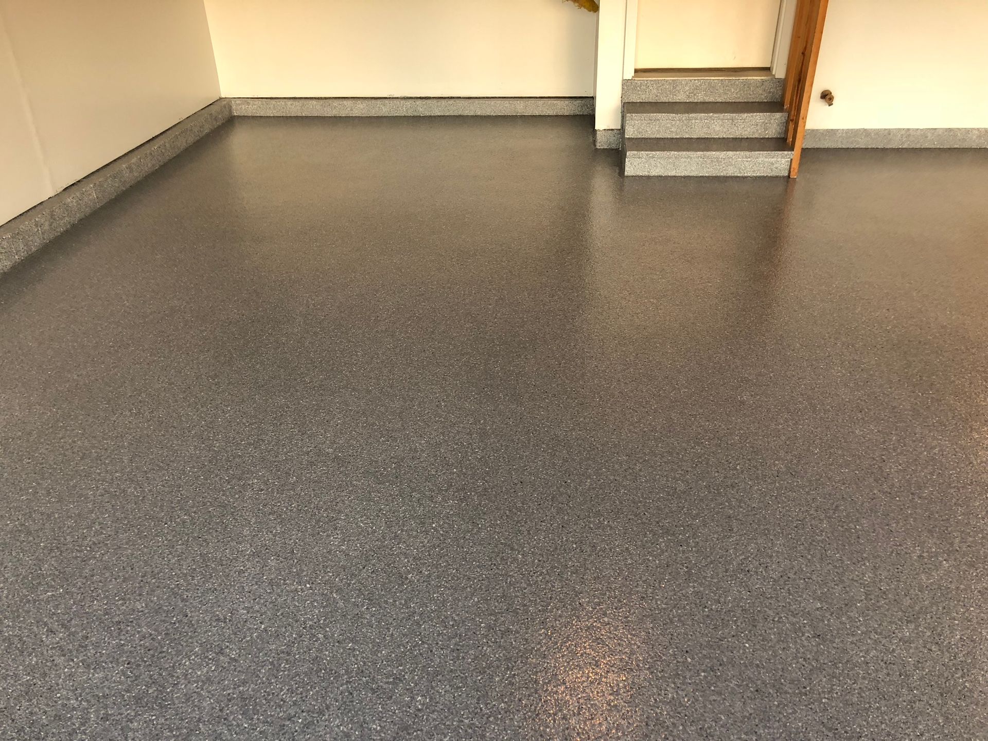 A garage with a staircase and a gray floor.