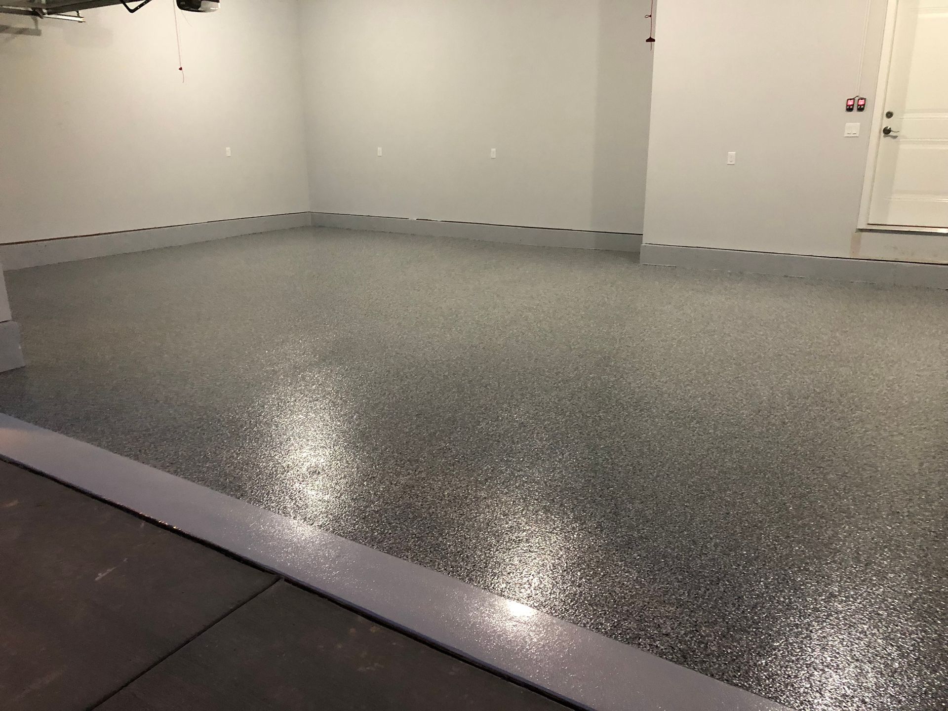 A garage with a shiny gray floor and white walls.