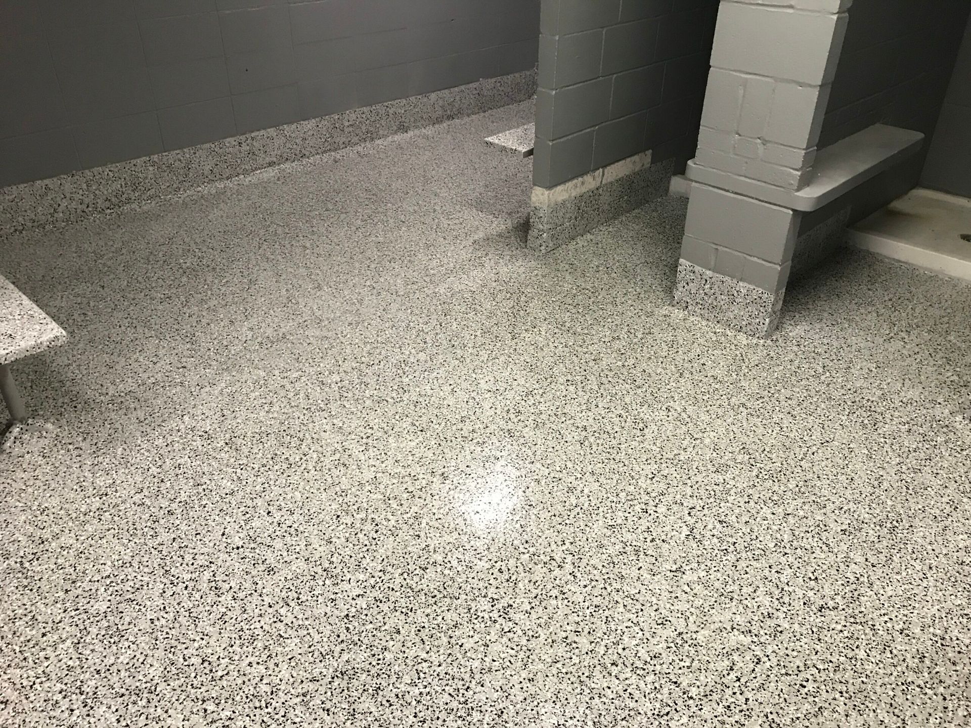 A bathroom with a concrete floor and a bench.