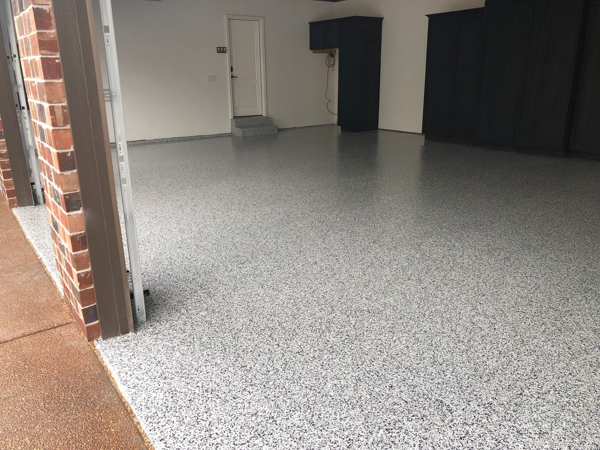 A garage with a concrete floor and a brick wall.