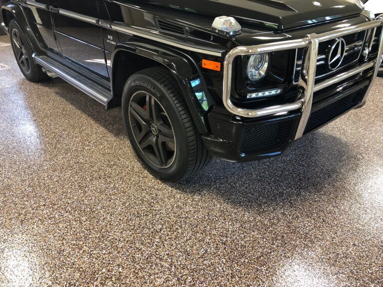 A black mercedes benz g63 is parked in a garage.