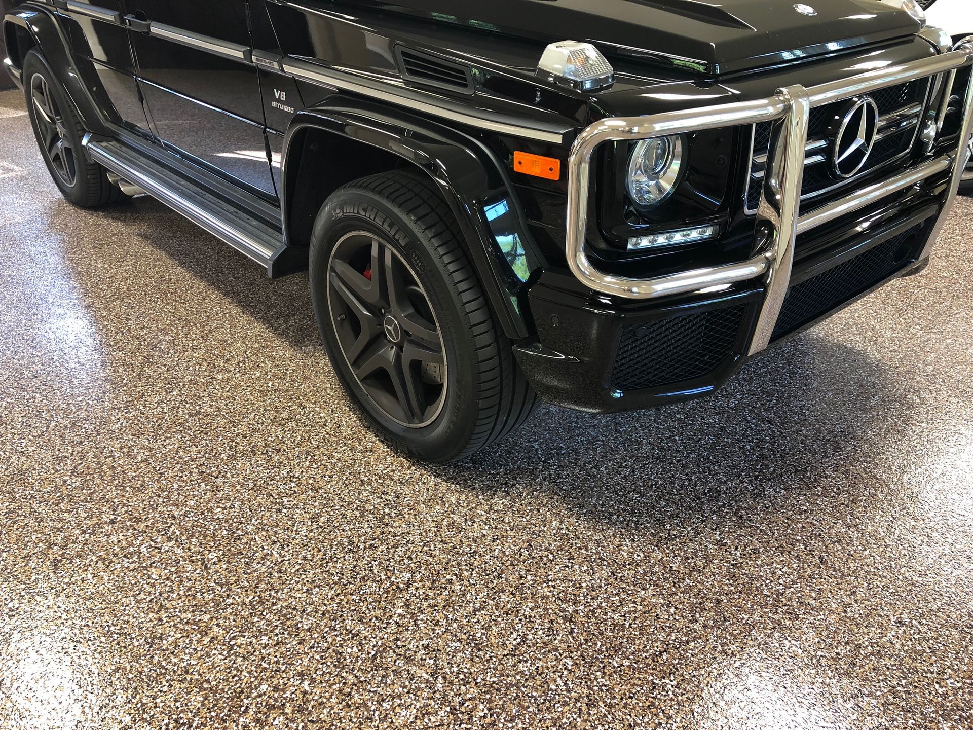 A black mercedes benz g class is parked in a garage.