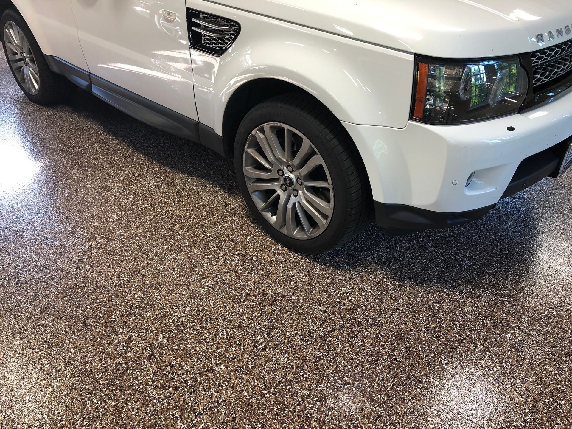 A white range rover sport is parked in a garage.