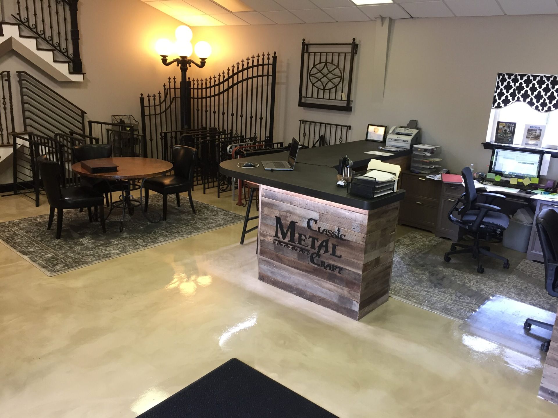 A room with a desk , chairs , tables and a staircase.