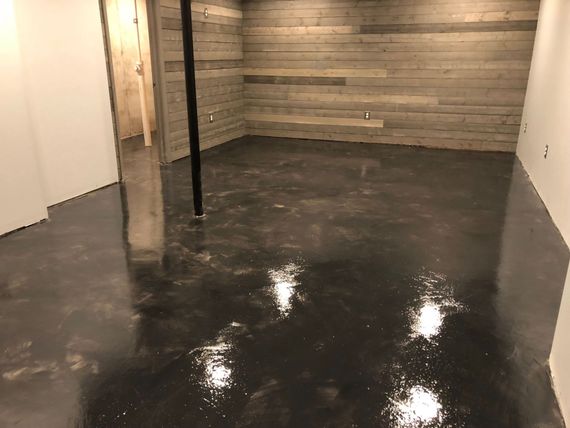 A basement with a concrete floor and a wooden wall.