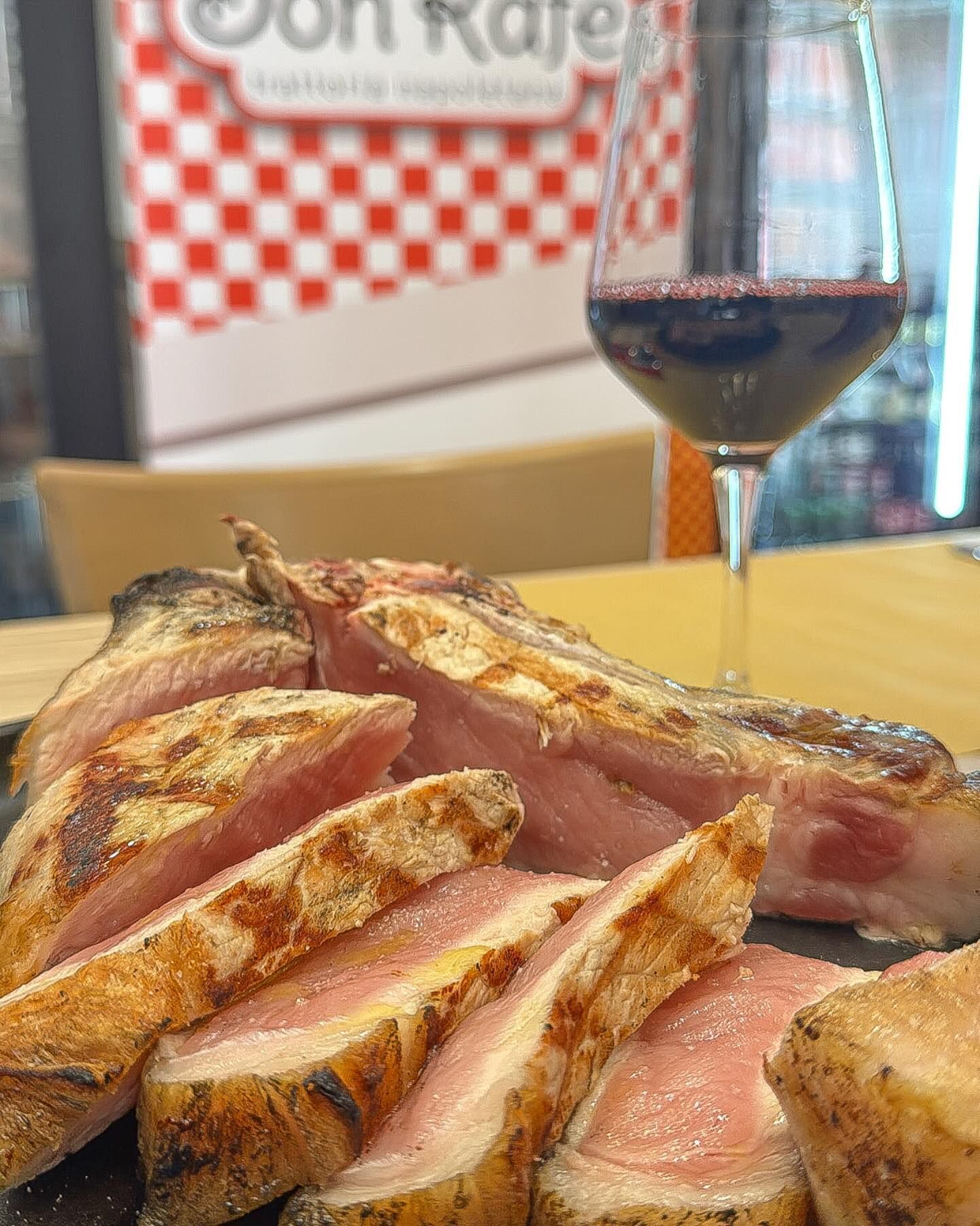 Un piatto di carne e un bicchiere di vino su un tavolo.