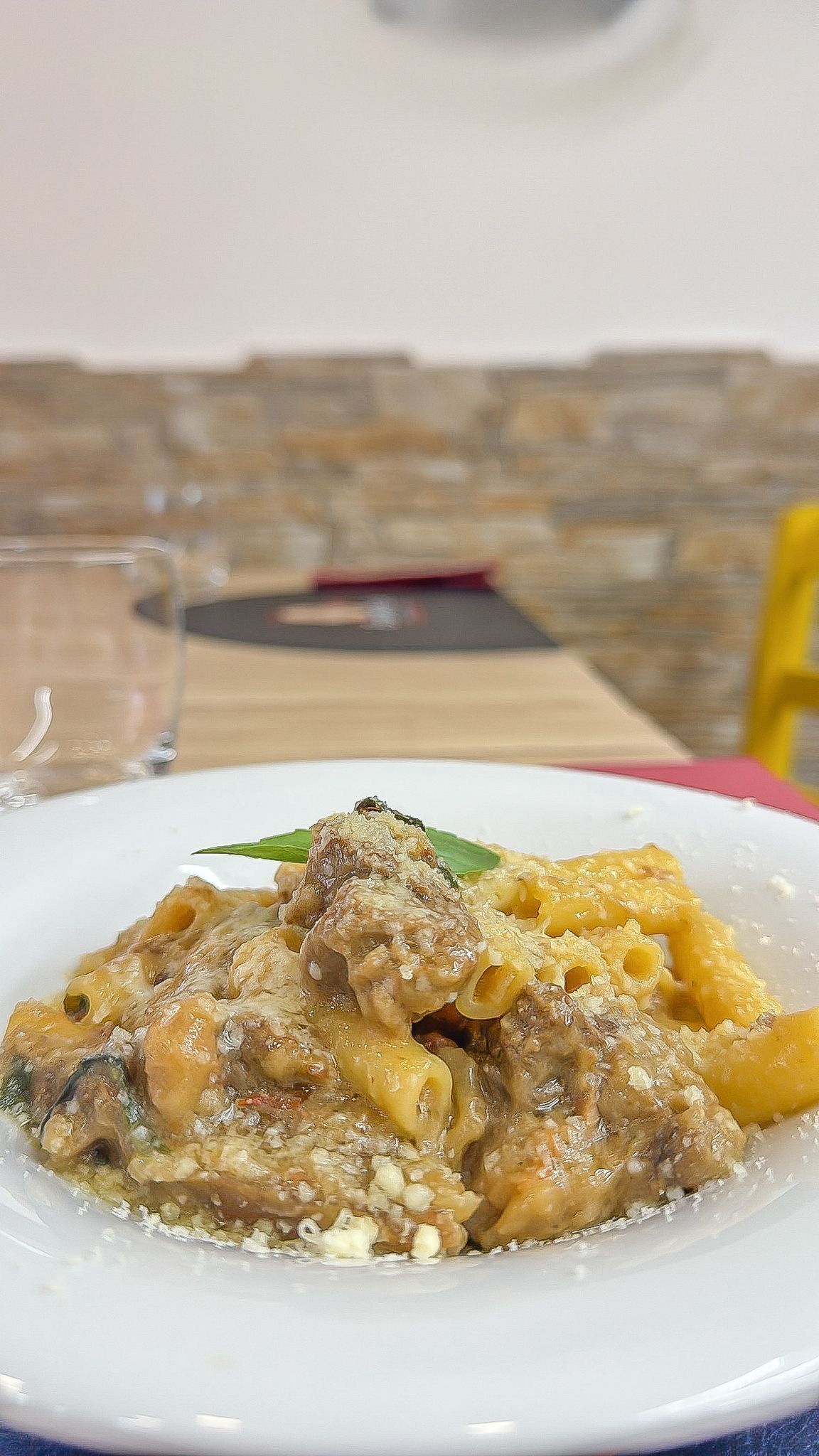 Una persona tiene in mano una ciotola rossa di pasta e polpette