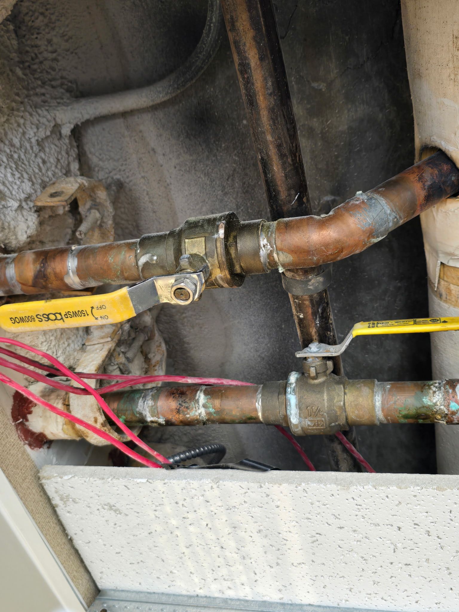 Person with red gloves connecting white plumbing pipes in a concrete setting.